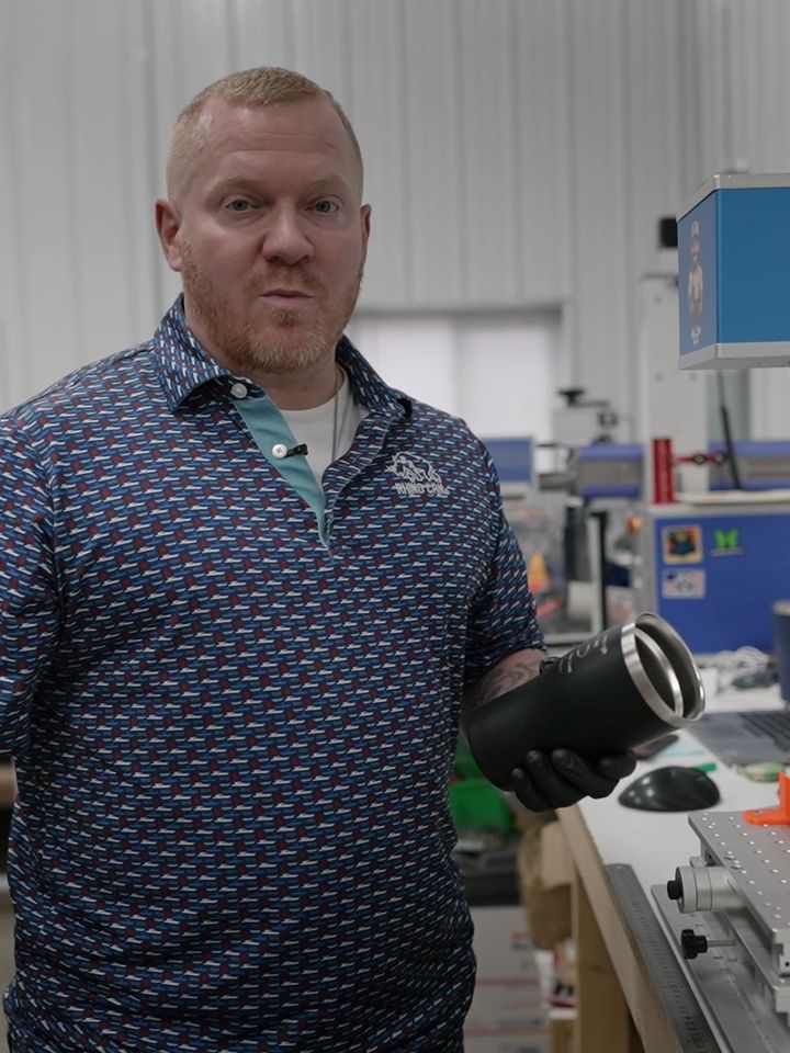 Abrasive Media Company owner holding an engraved tumbler in his laser shop