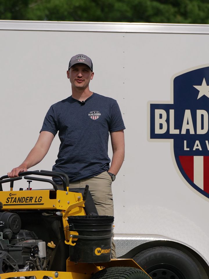 Blade Runner Lawn Care owner beside his stand-on mower in front of the branded trailer