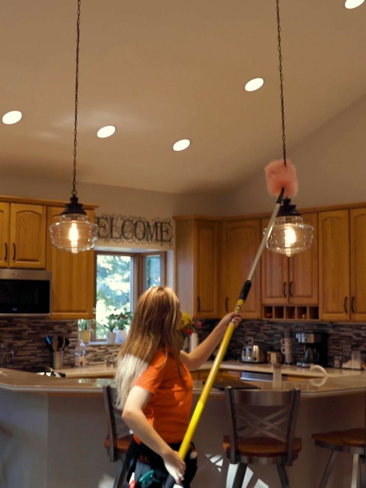 KODA Cleaning team member dusting a kitchen light with an extension duster