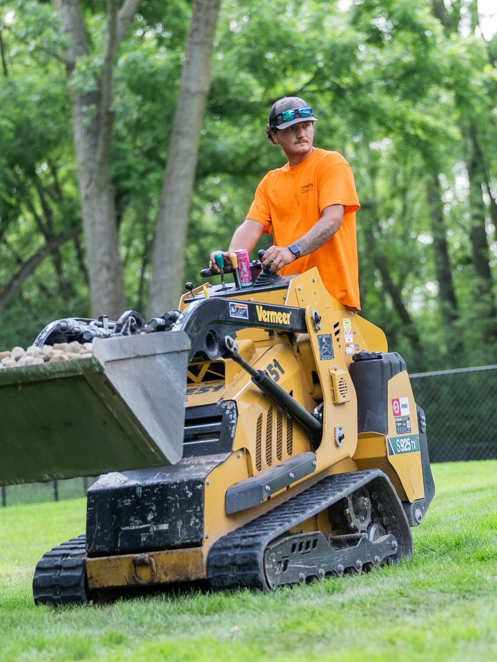 Rodas crew member driving a compact track loader across a lawn