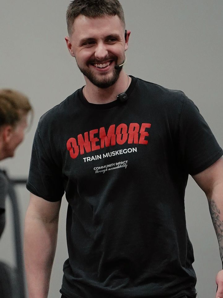 Train Muskegon coach smiling in a ONEMORE shirt on the gym floor
